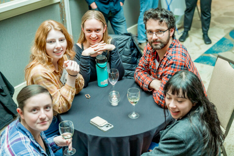 Group of people sitting around a table with wine.