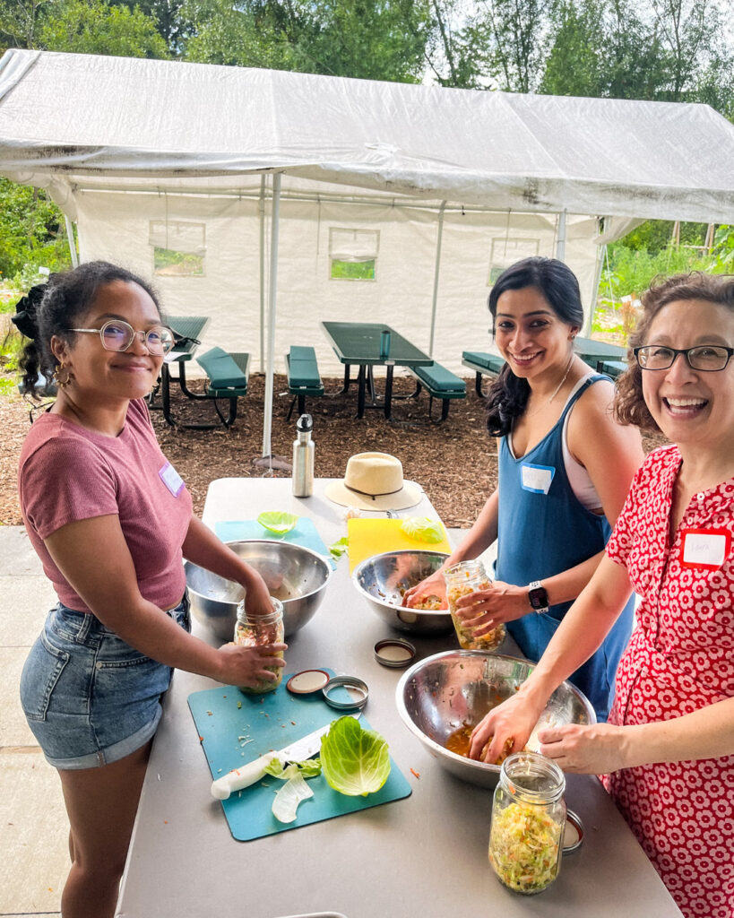 
Three women making fermented vegetables at outdoor cooking class